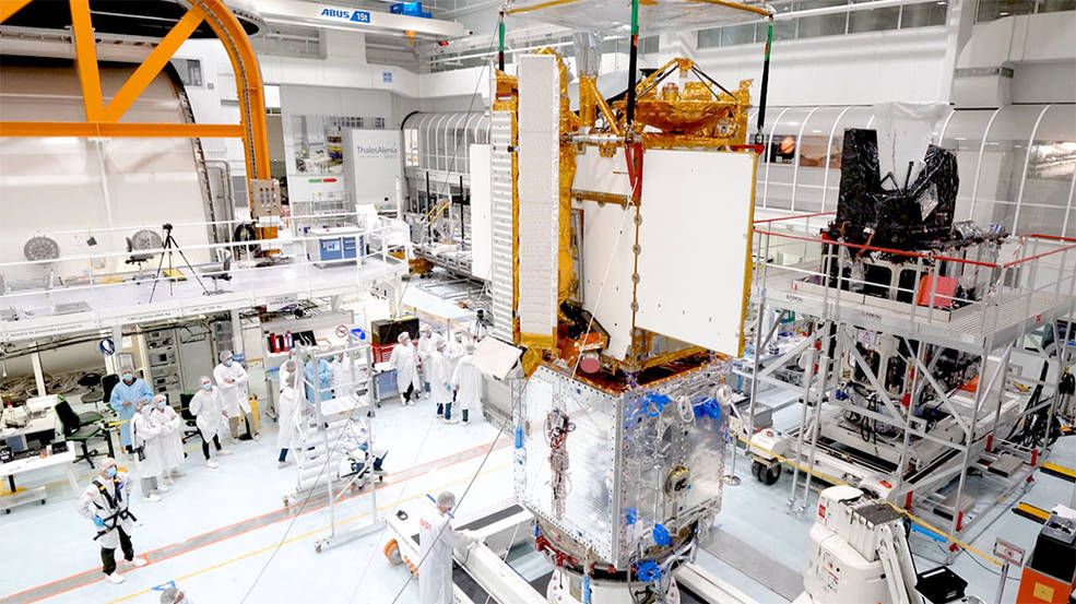 Photo depicting engineers integrating separate parts of the SWOT satellite into one in a clean room facility in Cannes, France.